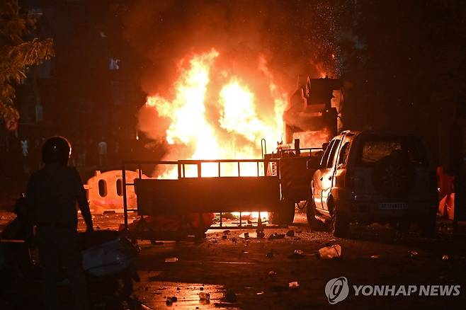 인도 소요사태 (나그푸르 AFP=연합뉴스) 17일 인도 중부 마하라슈트라주 나그푸르 치트나비스 공원 광장에서 소방 대원이 불타는 차량을 진화하기 위해 다가가고 있다. 2025.3.18. photo@yna.co.kr