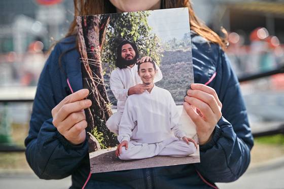 1995년 도쿄 지하철 사린 가스 공격에 연루돼 2018년 옴진리교의 다른 전 구성원들과 함께 사형된 니미 도모미쓰의 아내 니미 유키가 AFP와 인터뷰를 마친 뒤 교주 아사하라 쇼코와 함께 찍인 남편(사진 앞)사진을 들어보이고 있다. AFP=연합뉴스