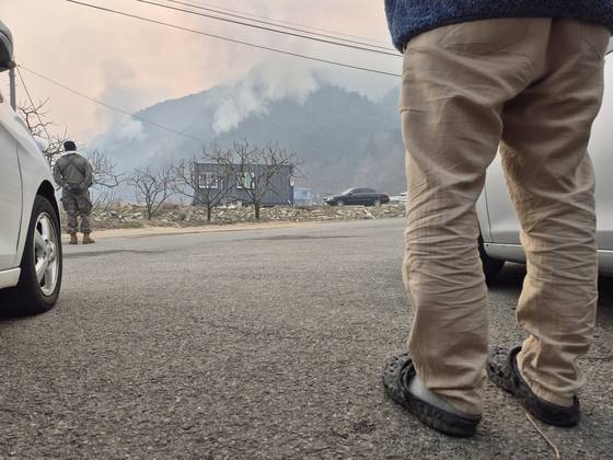 23일 오전 경남 산청군 시천면의 한 마을에서 산불이 민가로 내려올까 김모(40대)씨가 우려하고 있다. 대구에 사는 김씨는 전날 부모가 사는 이 마을까지 산불이 확산한다는 소식을 듣고, 슬리퍼 차림으로 산청을 급히 찾았다. 안대훈 기자