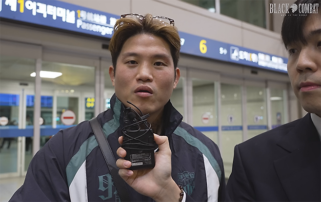 홍석현(오른쪽) 아나운서가 ‘최악의 코리안 갱스터 귀국 현장 인터뷰’에 출연한 초대 블랙컴뱃 웰터급 챔피언 결정전 참가 예정자 박원식 답변을 듣고 있다. 사진=이데아 파라곤 영상 화면