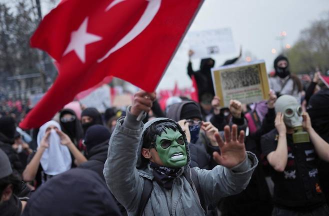 3월 23일 일요일 이스탄불에서 야당 정치인 이마모을루 체포에 항의하는 시위대가 국기를 흔들고 있다. 시위대는 경찰이 뿌리는 최루가스를 피하기 위해 마스크와 가면, 방독면 등을 썼다. AP 뉴시스