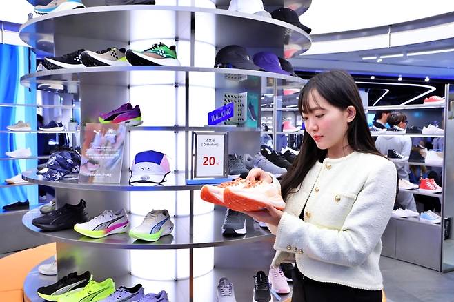 롯데백화점 본점 7층에 위치한 러닝슈즈존에서 모델이 상품을 들고 있다.