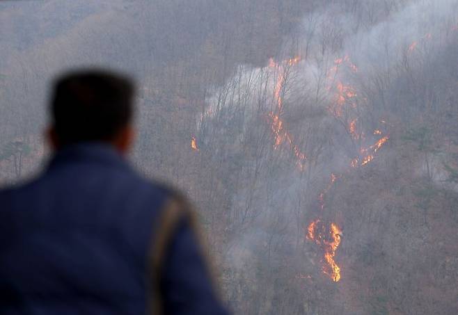 27일 경북 의성군 옥산면 금봉저수지에서 주민이 번져나가는 산불을 바라보고 있다. 연합뉴스