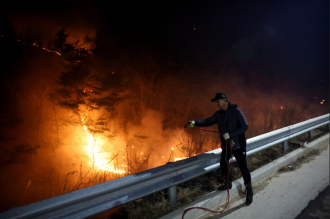 한 주민이 산불 확산을 막기 위해 물을 뿌리고 있다
