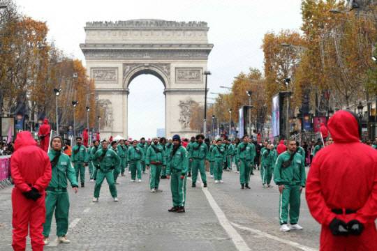 지난해 12월 1일 프랑스 파리의 번화가인 샹젤리제 거리에서 에투알 개선문을 배경으로 녹색 트레이닝복을 차려입은 참가자 456명이 ‘오징어 게임’ 놀이에 참여하고 있다. AFP 연합뉴스