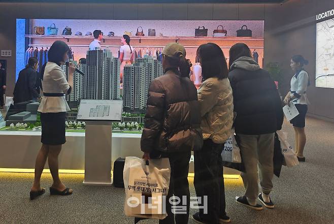 견본주택 방문객들이 아파트단지 모형도를 보고 있는 모습.