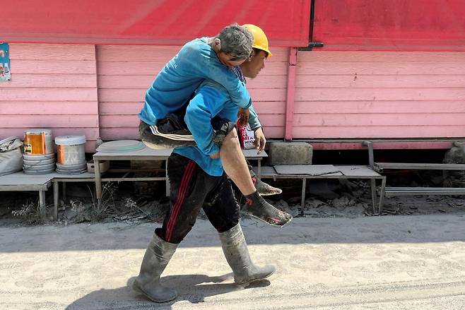 28일 태국 방콕을 강타한 지진 영향으로 무너진 건물에서 한 건설 노동자가 다른 노동자를 업은 채 길을 지나가고 있다. 로이터연합뉴스