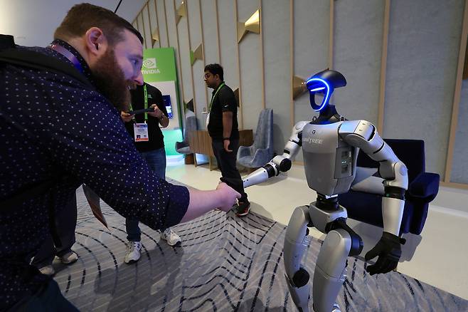 세계 최대 가전·정보기술(IT) 전시회 CES 2025가 개막한 지난 1월 7일(현지시간) 미국 네바다주 라스베이거스 퐁텐블루 호텔 엔비디아 전시관에서 휴머노이드 로봇 유니트리 G1이 한 관람객과 악수하고 있다. 연합뉴스