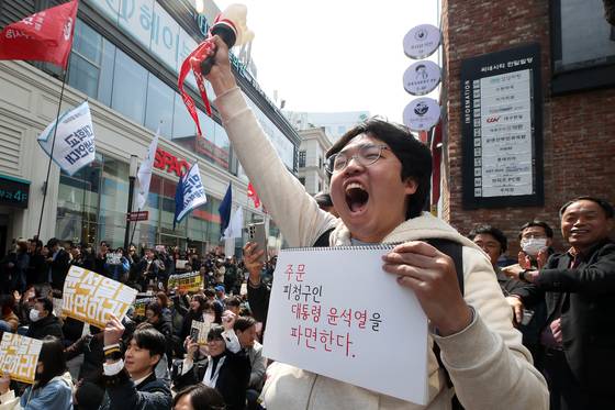 윤석열 대통령 탄핵심판 선고일인 4일 오전 문형배 헌법재판소장 권한대행의 판결문 낭독을 대구 동성로에서 지켜보던 한 시민이 스케치북에 미리 적어 온 주문을 들고 환호하고 있다. 뉴스1