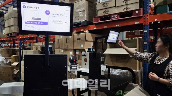 8일 경기 파주시 참물류 풀필먼트센터에서 한 직원이 트위니 자율주행 물류이송 로봇 ‘나르고 오더피킹’ 안내 화면을 확인하며 피킹 작업을 하고 있다.(사진=김범준 기자)