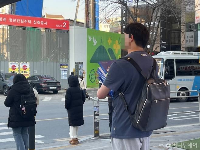 서울 동작구 노량진 학원가 일대에서 한 청년이 수험서 여러 권을 들고 있는 모습. /사진=이현수 기자.