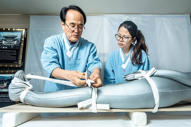 조유미 기자가 ‘대통령 염장이’라 불리는 유재철(왼쪽) 대장원 대표에게 ‘수시(收屍)’를 배우고 있다. 망자의 머리와 팔다리를 바로잡는 작업. /임화승 영상미디어 기자