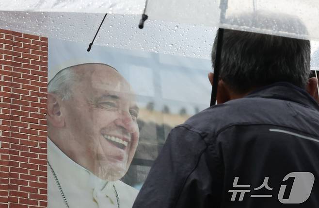 22일 오전 서울 중구 명동성당에서 관계자가 건물 외벽에 붙은 프란치스코 교황의 사진을 바라보고 있다. 2025.4.22/뉴스1 ⓒ News1 장수영 기자