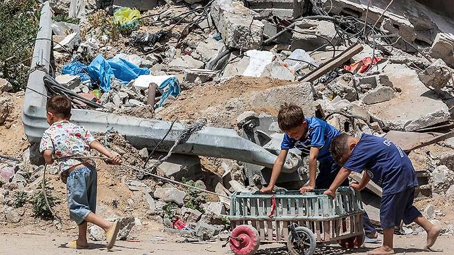 폐허 앞을 지나가는 가자지구 어린이들