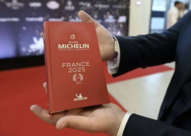 한 남성이 프랑스 미쉐린 가이드를 들고 있는 모습. 사진=AFP 연합뉴스
