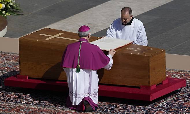 지난 26일(현지시간) 바티칸 성 베드로 광장에서 열린 프란치스코 교황의 장례식에서 디에고 라벨리(왼쪽) 대주교가 교황의 관 위에 성경을 올려 놓는 모습. AP연합뉴스