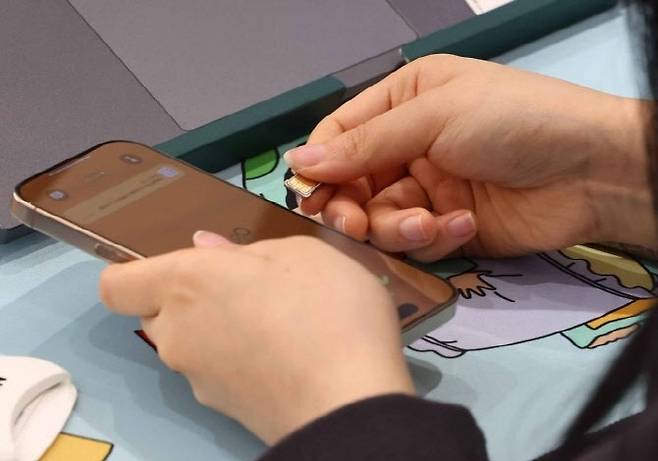 가입자 유심(USIM) 정보를 탈취당한 SK텔레콤이 유심 무료교체 서비스를 시작한 28일 서울 시내 한 SKT 대리점에서 직원이 유심 교체를 하고 있다.(사진=연합뉴스)