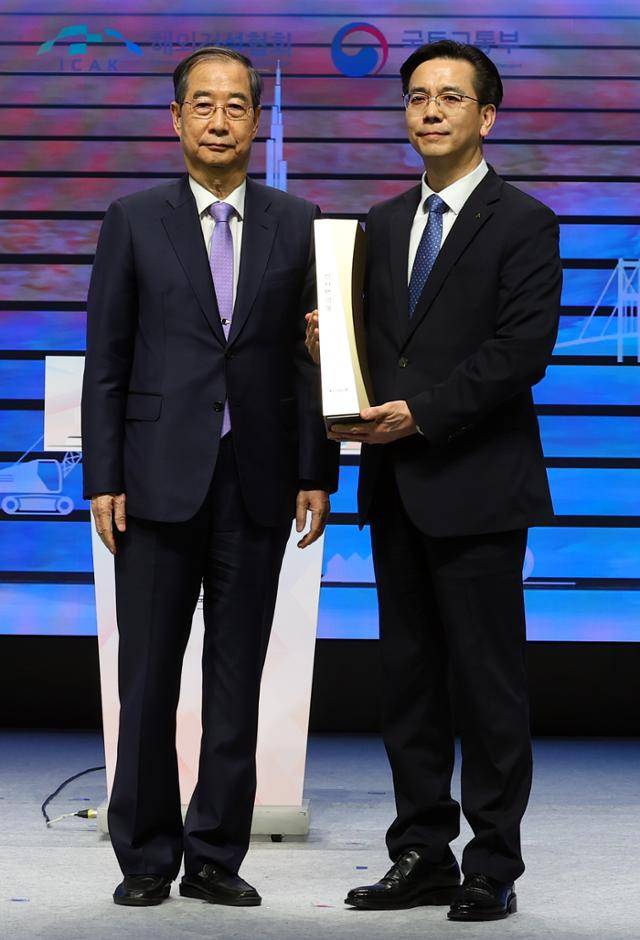 한덕수(왼쪽) 대통령 권한대행 국무총리가 29일 서울 강남구 건설회관에서 열린 해외건설 1조 달러 수주 및 60주년 기념식에서 이한우 현대건설 대표에게 해외건설의 탑을 수여 뒤 기념촬영하고 있다. 뉴시스