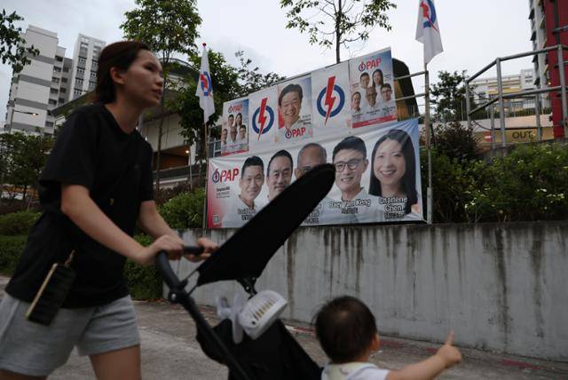 지난달 30일 싱가포르 주택가에서 한 시민이 인민행동당(PAP) 총선 후보자들의 얼굴이 담긴 현수막 앞을 지나고 있다. 싱가포르=EPA 연합뉴스