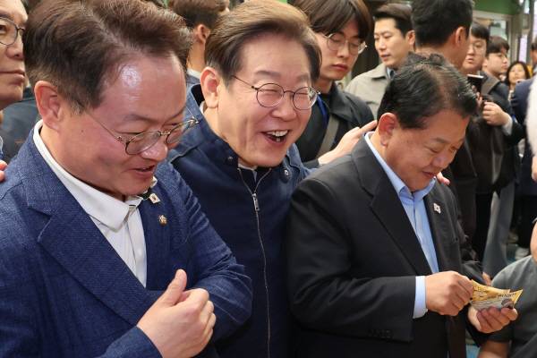 더불어민주당 이재명 대선 후보가 ‘골목골목 경청투어’ 접경지역 방문 이틀째인 지난 2일 강원도 인제군 원통전통시장에서 건어물 가게에 들러 황태채를 맛본 뒤 김병주(오른쪽)·허영 의원에게 구입을 권하고 있다. 연합뉴스