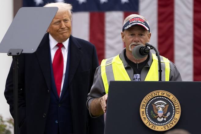 트럼프 대통령이 웃으며 미시간주의 자동차 노동자 출신 은퇴자 브라이언 페네베커(오른쪽)의 연설을 듣고 있다. 워싱턴=AP 뉴시스