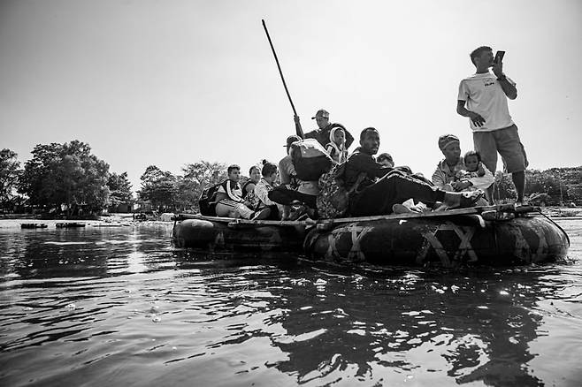 차 타이어에 판자를 덧댄 작은 보트를 탄 이민자들이 기대감과 걱정으로 강을 넘어 과테말라에서 멕시코에 들어온다. 강을 건너 오는데는 1달러를 지불한다. 벽으로 가는 긴 여정에는 2개의 큰 어려운 지역이 있다. 하나는 라셀바라고 불리는 콜롬비아와 파나마 사이의 정글 (정식명칭 : Darian gap)과 멕시코다. 많은 이민자들은 라셀바 보다 멕시코가 훨씬 위험하고 힘들다고 입을 모아 말한다. 2024. 02. 멕시코, 치아파스 주 멕시코와 과테말라 국경/ 사진가 양희석