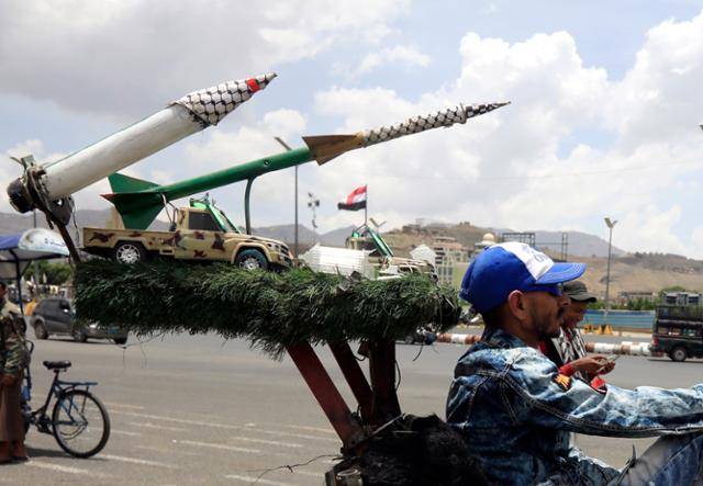 예멘 수도 사나의 한 길거리에서 미사일이 놓인 가운데 사람들이 자전거를 타고 지나가고 있다. 사나=EPA 연합뉴스