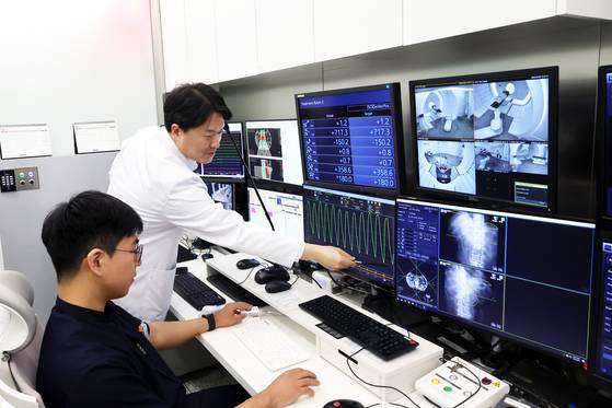 29일 오전 세브란스병원 중입자치료센터에서 금웅섭 센터장(사진 오른쪽 서있는 사람)이 이종윤씨의 치료를 진행하고 있다. 환자의 호흡 주기에 맞춰 숨을 내쉬어 몸이 완전히 정지된 상태에 중입자 에너지빔이 조사된다. 장진영 기자.