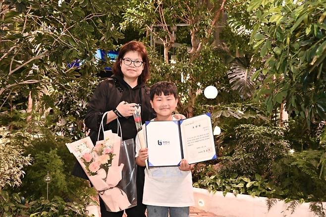 This photo distributed by Bucheon city officials shows Jeong Tae-wun (right) posing with his certificate of appreciation with his mother last Thursday at the Children's Day ceremony at the city hall. (Courtesy of Bucheon city)