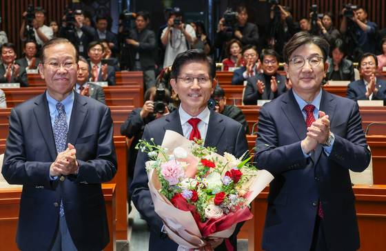김문수 국민의힘 대통령 후보가 9일 서울 여의도 국회에서 열린 의원총회에서 꽃다발을 받은 뒤 기념 촬영하고 있다. 왼쪽부터 권영세 비대위원장, 김 후보, 권성동 원내대표. 김 후보는 지도부를 향해 "무소속을 당 후보 만들려 불법부당 수단 동원, 중단하라"며 입장을 밝힌 뒤 의총장을 떠났다. 뉴스1