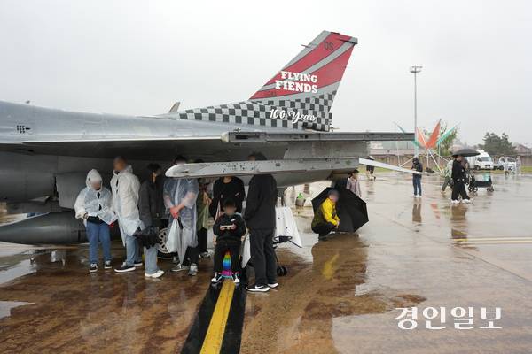 지난 10일 미 7공군 소속 51 전투비행단이 주최한 ‘오산 에어 파워데이 2025’에 참석한 관람객들이 전투기 날개 아래에서 비를 피하고 있다. 2025.5.10 평택/김종호기자 kikjh@kyeongin.com