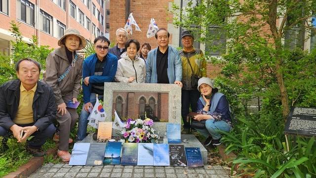 일본 교토 예술대학 다카하라 캠퍼스에 위치한 윤동주 시비 앞에서 시화전을 열고 기념사진을 찍고 있다. 사진=신석정기념사업회 제공