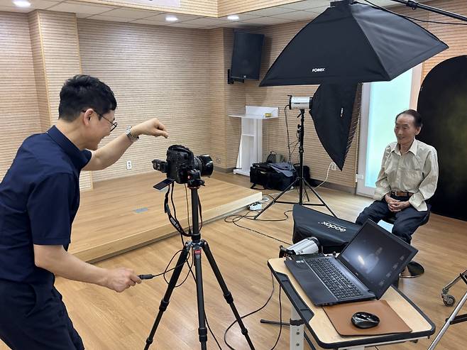 스튜디오 경력 20년차 권정운 은광교회 집사가 12일 서울 은평구 불광1동 주민센터에서 김학식 할아버지를 촬영하고 있다.