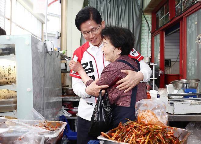 국민의힘 김문수 대선 후보가 14일 경남 진주시 진주중앙시장을 방문해 반찬을 구매하고 상인과 포옹하고 있다. <연합>