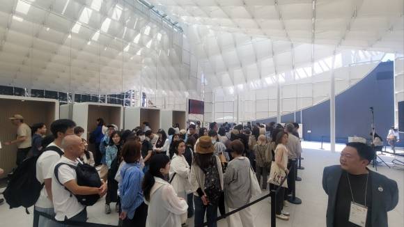 지난 13일 오사카·간사이 엑스포 한국관 외부에 관람객들이 입장을 기다리며 길게 줄을 서 있다. 왼쪽으로 관람객들이 녹음 부스에서 녹음을 하고 있는 모습이 보인다. 오사카 이주원 기자