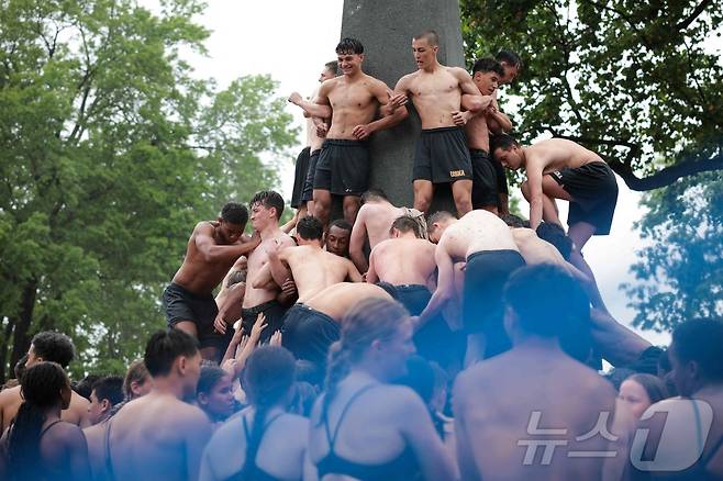 미국 해군사관학교에서 사관생도들이 14일(현지시간) 미국 메릴랜드 주 아나폴리스 미 해군 사관학교에서 '딕시 컵'을 떨어뜨리기 위해 인간 피라미드를 만들어 헌던 기념물 꼭대기에 오르고 있다. ⓒ AFP=뉴스1