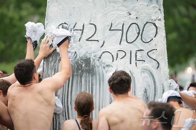 미국 해군사관학교에서 사관생도들이 14일(현지시간) 미국 메릴랜드 주 아나폴리스 미 해군 사관학교에서 '딕시 컵'을 떨어뜨리기 위해 인간 피라미드를 만들어 헌던 기념물 꼭대기에 오르고 있다. ⓒ AFP=뉴스1