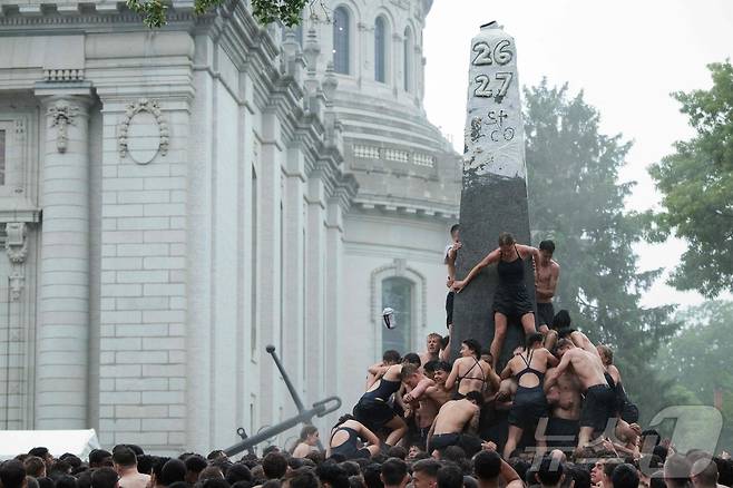 미국 해군사관학교에서 사관생도들이 14일(현지시간) 미국 메릴랜드 주 아나폴리스 미 해군 사관학교에서 '딕시 컵'을 떨어뜨리기 위해 인간 피라미드를 만들어 헌던 기념물 꼭대기에 오르고 있다. ⓒ AFP=뉴스1