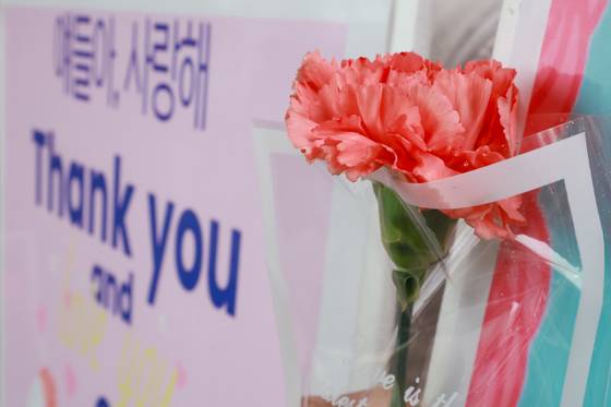 스승의날인 15일 서울 성동구 서울방송고등학교에서 등교하는 학생들을 맞이하는 교사가 카네이션과 손팻말을 들고 있다. 연합뉴스