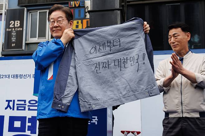 이재명 더불어민주당 대선후보가 14일 오후 경남 창원 상남분수광장 집중유세에서 “이제부터 진짜 대한민국!”이 적힌 작업복을 전달 받고 있다. 김성룡 기자
