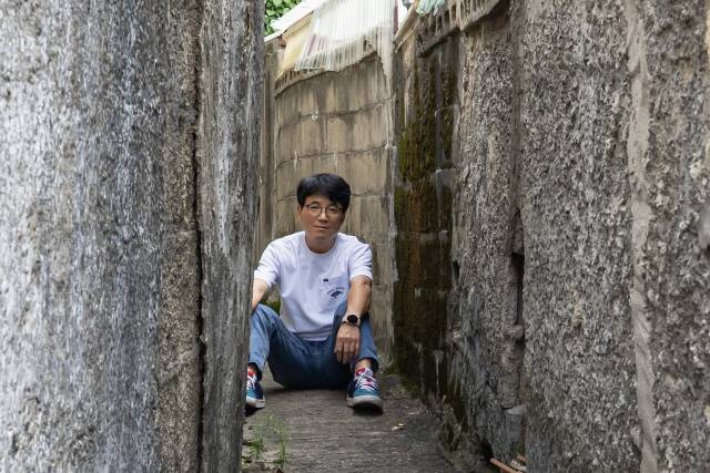 ▲ 춘천의 한 골목에 앉아 포즈를 취하는 이수환. 그는 늘 자신을 ‘사진작가’ 대신 ‘사진가’로 불러주길 원했다.
