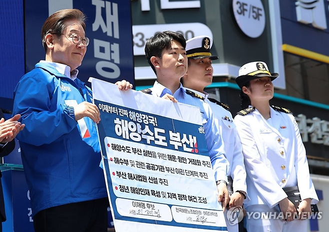 이재명 더불어민주당 대선 후보가 14일 부산 부산진구 서면 젊음의 거리에서 열린 유세에서 권기흥 에이치라인해운해상직원노조 위원장과 해양수도 부산 협약서에 서명한 후 기념 촬영을 하고 있다. <연합뉴스>