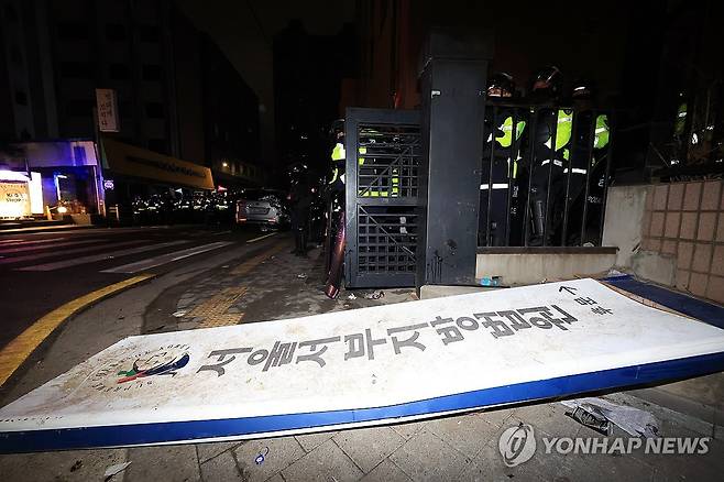 윤 대통령 구속 뒤 지지자 일부 서부지법 난입 (서울=연합뉴스) 신현우 기자 = 윤석열 대통령이 내란 우두머리 혐의로 구속되자 지지자들이 서울 마포구 서울서부지방법원에 난입한 19일 오전 경찰이 서부지법 후문에 현판이 쓰러져 있다. 2025.1.19 nowwego@yna.co.kr