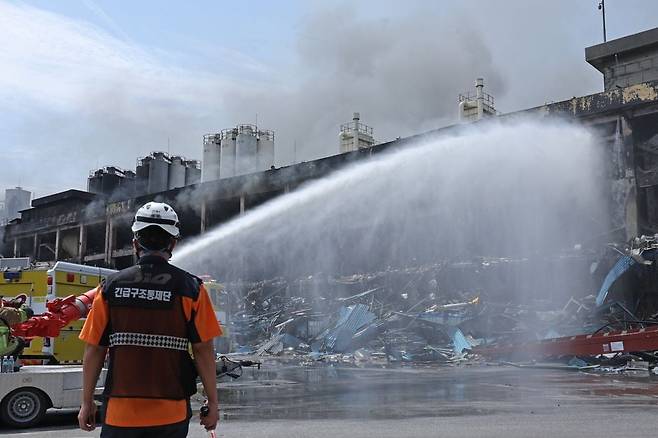 금호타이어 광주공장 화재 발생 이틀째인 18일 불이 난 2공장에서 연기가 나는 가운데 소방대원들이 물줄기를 쏘며 진화 작업을 벌이고 있다. 연합뉴스