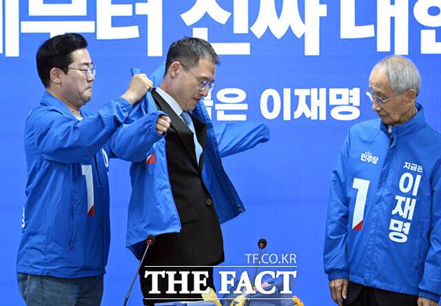 국민의힘 탈당 후 이재명 더불어민주당 대선 후보 지지에 이어 민주당에 입당한 김상욱 의원(가운데)이 19일 서울 여의도 더불어민주당 중앙당사에서 열린 중앙선거대책위원회의에 참석해 박찬대 원내대표의 도움으로 당 점퍼를 착용하고 있다. 오른쪽은 윤여준 총괄상임선거대책위원장. /박헌우 기자