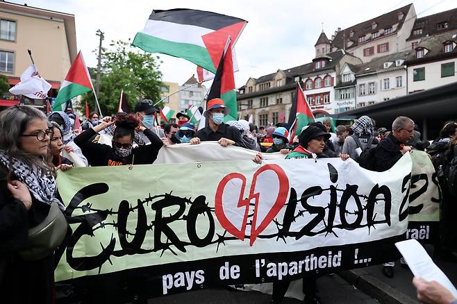유로비전 송 콘테스트 결선이 열린 17일 경연 장소인 스위스 바젤의 한 거리에서 친팔레스타인 시위대가 이스라엘 가수의 참여에 항의하며 '인종차별의 나라'라고 적힌 플래카드를 들고 있다. /로이터 연합뉴스