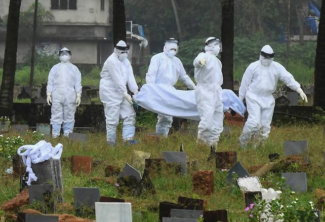 인도 남부 케랄라주 코지코드에서 방역복을 입은 인부들이 니파 바이러스(Nipah Virus)로 사망한 환자의 시신을 화장하기 위해 이송하고 있다. AP 연합뉴스
