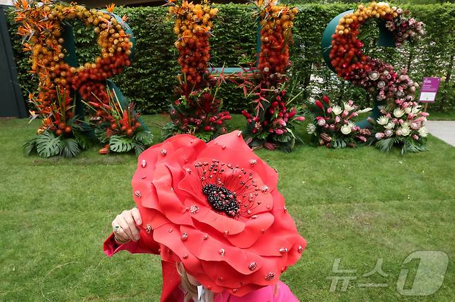 19일(현지시간) 영국 런던에서 열린 RHS 첼시 플라워쇼 프리뷰 행사에서 꽃무늬 머리장식을 한 시민이 방문하고 있다. ⓒ 로이터=뉴스1