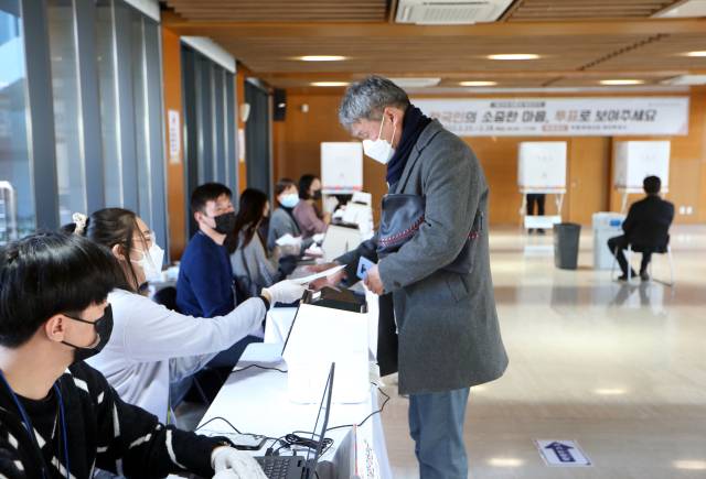 제20대 대통령 선거 재외투표 첫날인 23일 중국 베이징 주중대사관에 설치된 투표소에서 한 교민이 투표지를 받고 있다. 연합뉴스