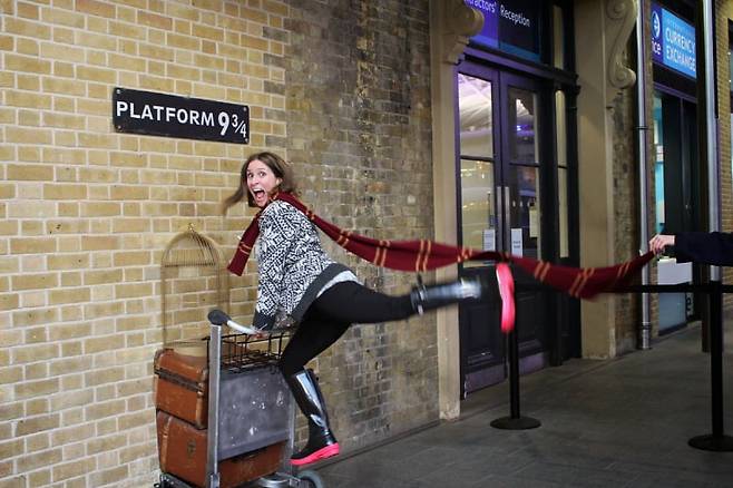 영국 해리포터촬영지 킹스크로스역 9와 4분의 3 승강장에서 조형물과 함께 기념사진을 찍고 있는 관광객. 사진=트래블뷰 제공